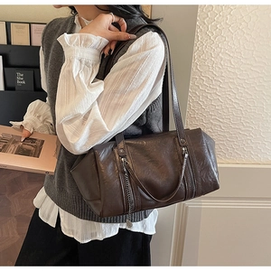 Detail of dark brown vintage faux leather shoulder bag with pleats and metal chain pendant