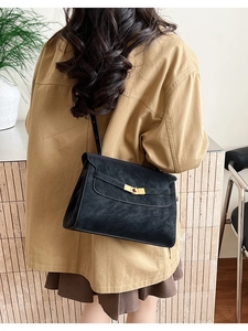 Model view showing the scale of the black leather shoulder bag with gold hardware