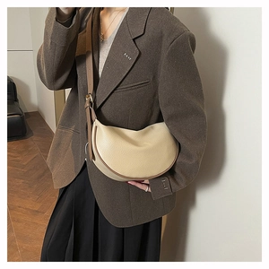 Detail view of cream white pebble leather crescent bag with brown adjustable strap and gold hardware