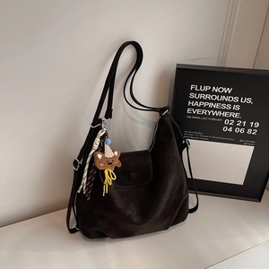 Detail of black matte PU leather tote bag with bear charm and striped tassel decor