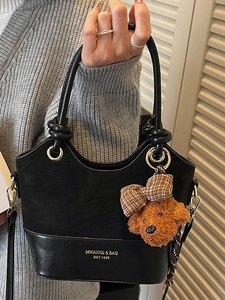 Chic black handheld crossbody bag with gold buckle and cute brown puppy plush charm