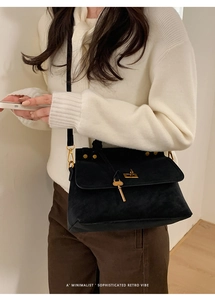 Chic black suede crossbody bag featuring gold twist lock and unique key charm detail