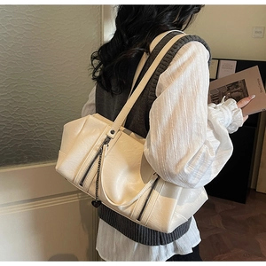 Detail of off-white faux leather tote bag with double zippers and heart charm