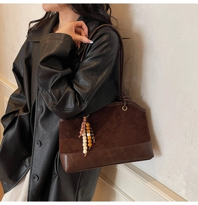 Detailed close-up of dark brown suede shoulder bag with vintage decorative beads