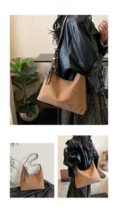 Detail showing vintage brown suede tote bag with contrast stitching and metal tassel charm