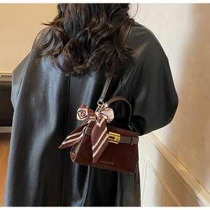 Close-up of retro brown crossbody bag with suede texture and patterned silk scarf handle