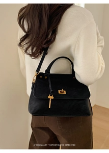 Detail of vintage black suede handbag with gold lock and adjustable leather shoulder strap
