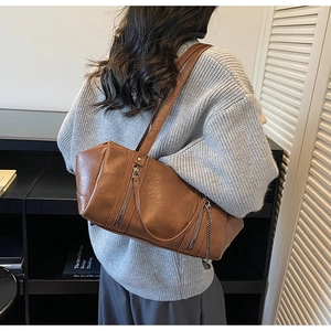 Detail of vintage brown PU leather shoulder bag with decorative metal zippers and chain