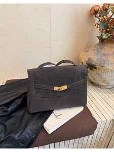 Detailed close-up of retro leather tote bag with metallic swivel lock and top handle
