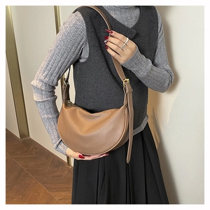 Detail of a brown lychee pattern leather crescent bag with adjustable gold buckle strap