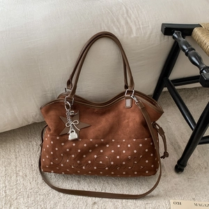 Dettaglio della borsa tote in pelle scamosciata marrone con pois bianchi e ricamo elegante