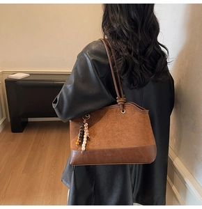 Detail of vintage brown tote bag with suede patchwork and ethnic bead accessory