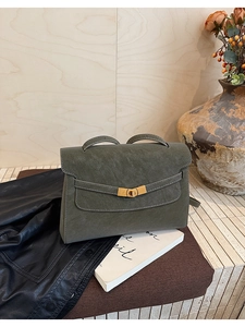 Detailed view of dark green suede tote with golden twist-lock and contrast stitching