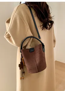 Detail of dark brown suede bucket bag with decorative wooden beads and leather tassels
