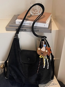 Large black tote bag with cute bear charm and adjustable straps on a minimal background