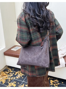 Detail of suede hobo bag featuring fashion lettering and woven tassel on shoulder strap