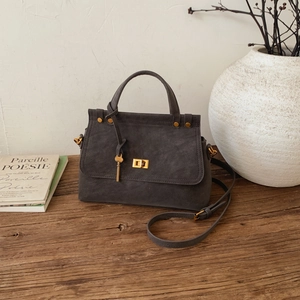 Close-up of retro dark gray suede handbag with gold square twist lock and key charm