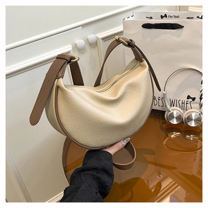Detailed macro view of beige lychee leather crescent bag with adjustable brown strap