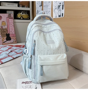 Détail du sac à dos scolaire bleu clair avec imprimés étoiles et poches zippées multiples