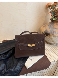 Detail of vintage dark brown tote bag with lychee texture and golden twist lock closure