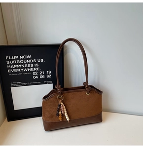 Detail view of brown vintage shoulder bag with suede texture and wooden beaded tassel