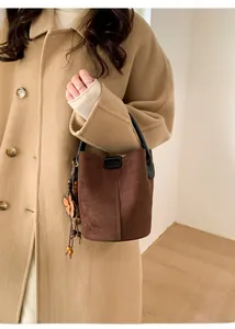 Detail of a brown suede bucket bag featuring a wooden beaded flower charm on the side