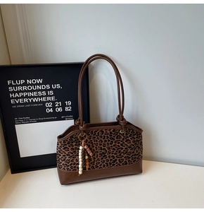 Detail of leopard print tote bag with brown leather handles and decorative beads