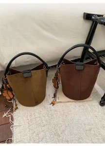 Close-up of suede bucket bags with wooden bead floral charms on cream plush rug