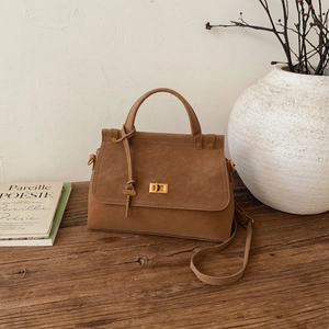 Close-up of vintage brown suede handbag with golden twist lock on rustic wooden surface