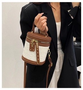 Close-up of brown and white contrast bucket bag with heart embossed leather and gold hardware