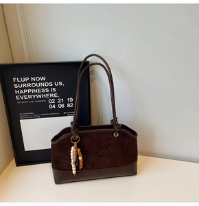 Detail of dark brown vintage suede tote bag with slim handles and colorful beaded charm