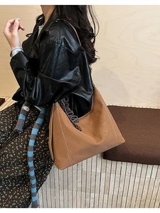 Close-up of large caramel tote bag with white stitching and brand logo details