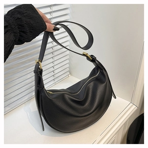 Close-up of black lychee-textured crescent bag with a gold metal strap buckle