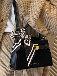 Retro black leather handbag with a silk scarf tied to the handle and a gold clasp