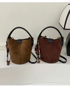 Close-up of retro bucket bags in khaki brown and dark coffee with decorative tassels