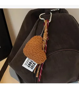 Nahaufnahme eines herzförmigen Taschenanhängers aus Fleece mit Kordel an braunem Rucksack