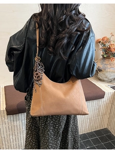 Detail of caramel brown hobo bag with large Bingo pendant and thick decorative stitching