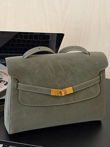 Olive green suede trapezoid tote bag with metal twist lock in a modern office setting