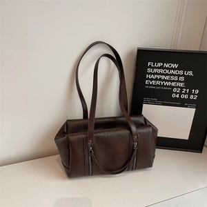 Close-up of retro brown faux leather bag featuring dual silver zippers and long straps