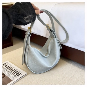 Detail view of grey-blue dumpling hobo bag with pebbled leather texture and gold metal buckles