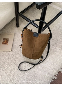 Detailed overhead view of a brown suede bucket bag with beaded tassels and black leather trim
