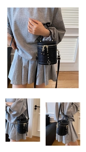 Detail view of black quilted cylinder bucket bag with gold zippers and long strap