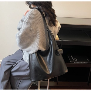 Side view of large black matte faux leather hobo bag showing casual drape and spacious size