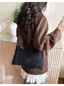 Detail of black tote bag showing white contrast stitching and unique decorative charms