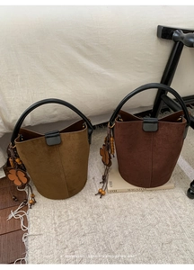 Detail of suede bucket bags with leather floral charms and elegant wood bead tassels