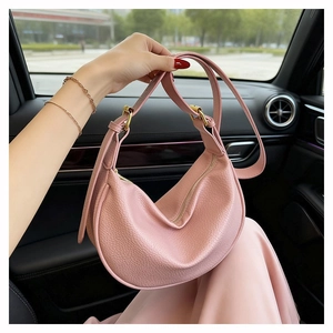 Detailed close-up of pink crescent bag with lychee grain leather and golden hardware