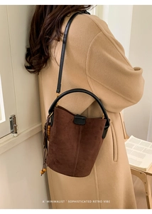 Detail of dark brown suede bucket bag with leather handle and wooden bead tassel