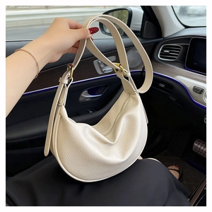 Detailed macro view of beige lychee-patterned leather dumpling bag with gold hardware
