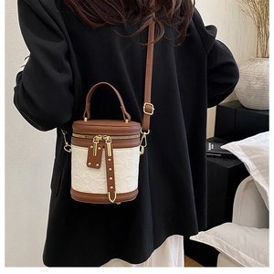 Detail showing the mixed-material texture and gold hardware of the bucket crossbody bag