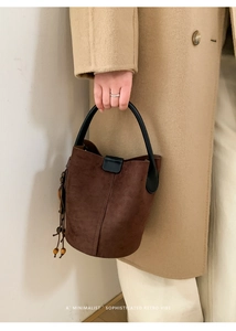Detail of retro dark brown suede bucket bag with wooden bead tassels and black handle